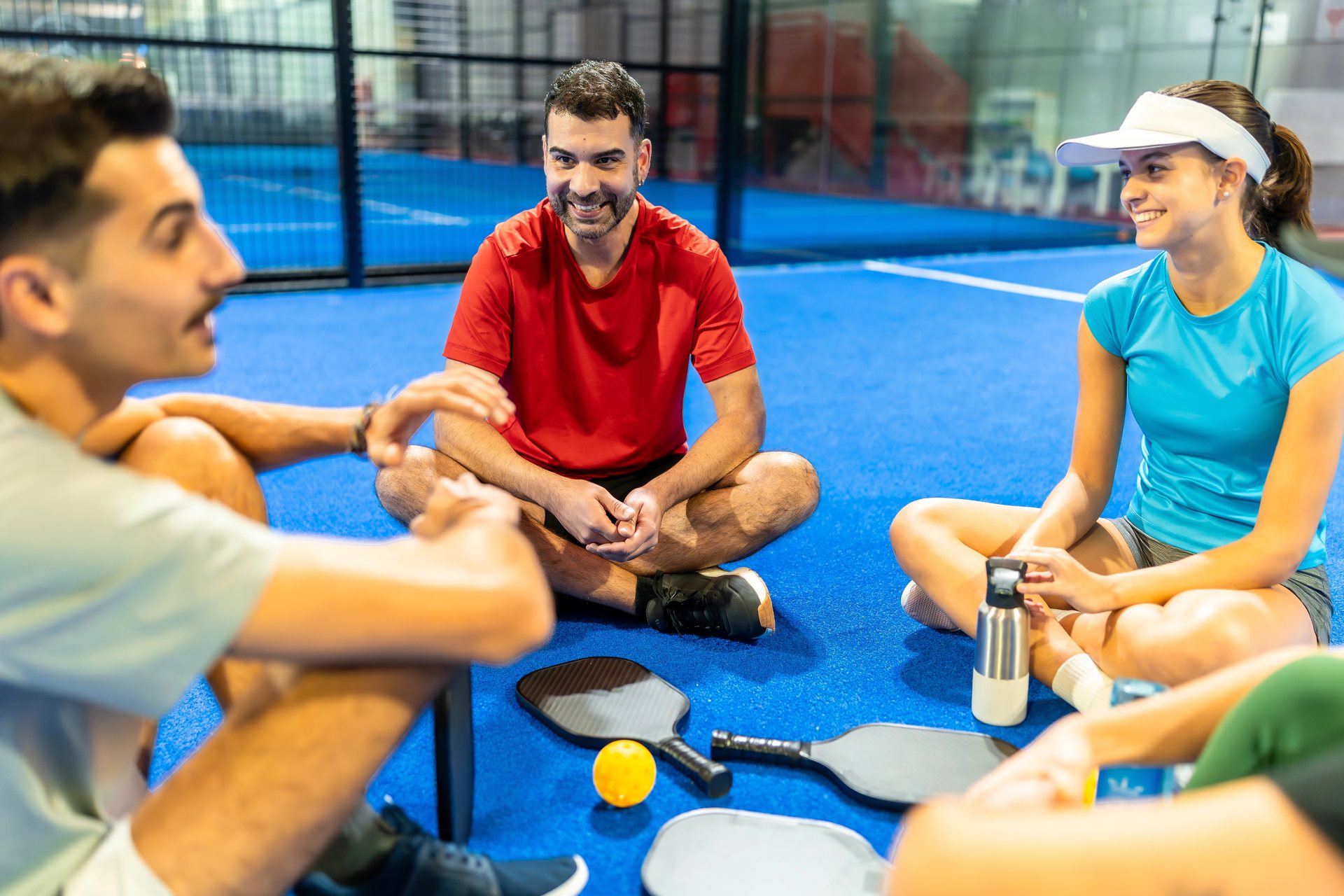 Grupo de jugadores charlando en la pista con sus palas de pickleball